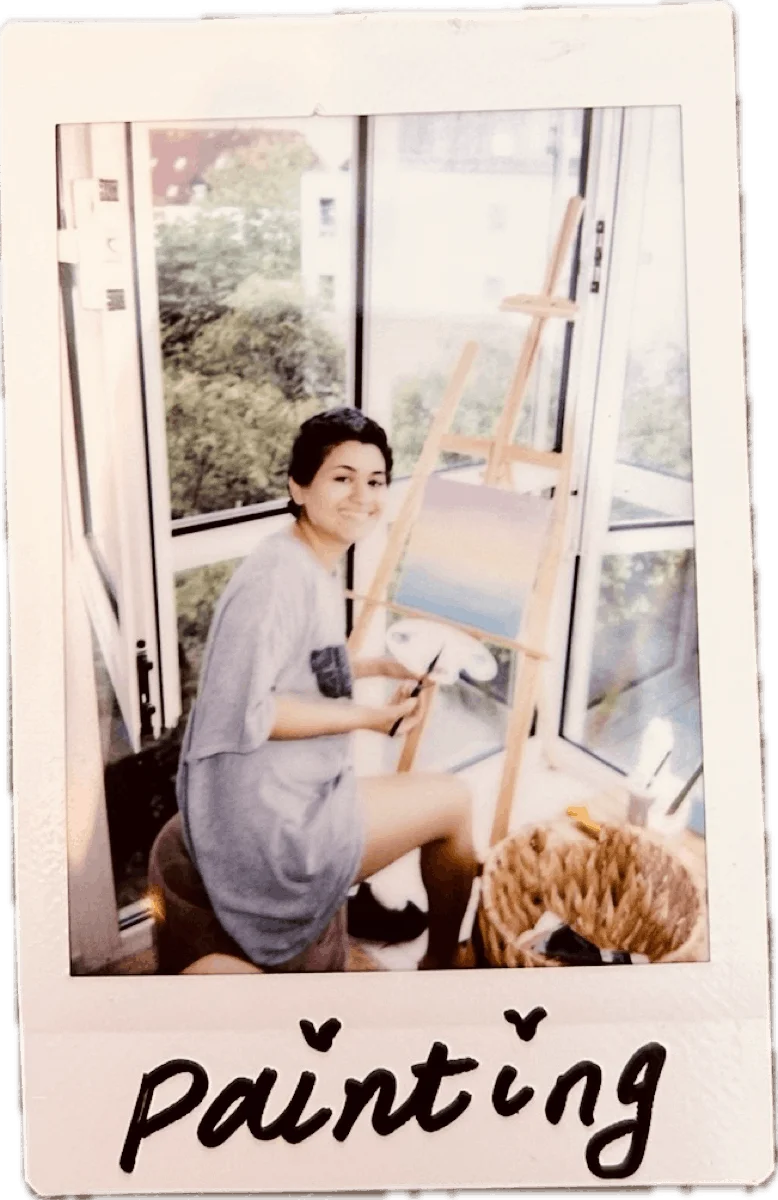 Sahar painting at an easel by a window