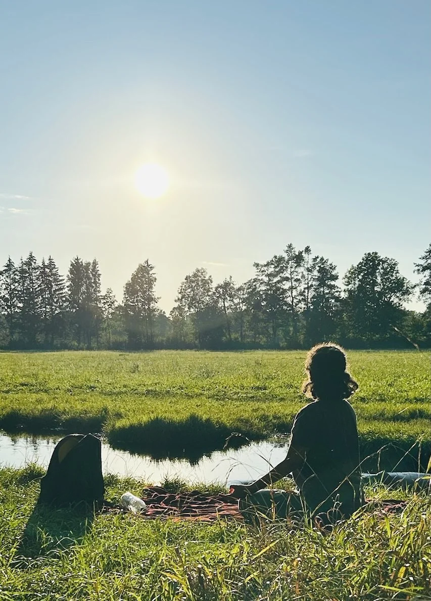Sahar sitting in a meadow at sunset